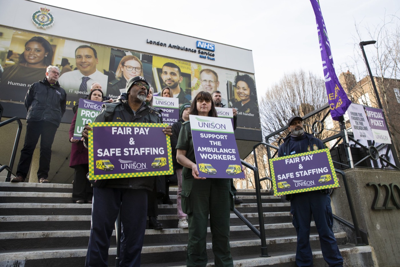 Ambulance workers on the picket line outside an LAS station holding ‘Fair Pay & Safe Staffing’ and ‘Support the Ambulance Workers’ placards, 2023.
